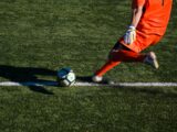 man kicking soccer ball on field