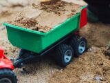 selective focus photo of toy trailer filled of brown sands