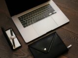 black leather bifold wallet beside macbook pro