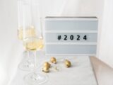 Elegant New Year's Eve setup with champagne glasses, golden Christmas balls, and a 2024 sign.