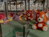 Vibrant plush toys including dragons and mice in an urban shop display. Perfect for toy enthusiasts.