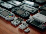 Collection of diverse retro handheld gaming consoles on a wooden surface, showcasing classic designs and nostalgia.