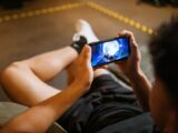 Man playing a video game on a smartphone while sitting comfortably indoors.