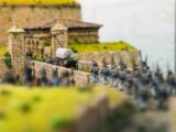 Miniature soldiers march past a stone fort