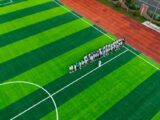 A group of people standing on a green soccer field.
