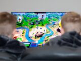 two boys are playing a video game on the television