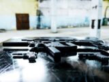 Various firearms displayed on a scratched metal table in an industrial setting.