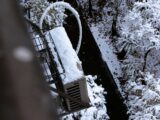 Snow covered industrial equipment next to trees