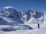 Stunning winter landscape of the snowy Swiss Alps with a solitary person at a mountain peak.