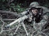 marksman holding sniper rifle near plants