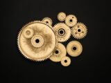 Close-up of golden cogs and gears arranged on a black background showcasing industrial precision.