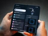 Hands holding a foldable smartphone displaying settings menu