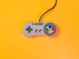 white nintendo game controller on yellow surface
