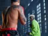 Two fighters engaged in cosplay-themed martial arts sparring inside a warehouse.
