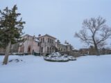 A picturesque historic manor surrounded by snow in a winter setting.