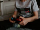 kid sitting on gray bed while playing