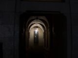 Dark arched hallway with a light at the end