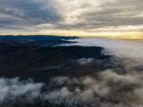Foggy mountain range with sunlit ocean horizon