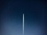 A rocket streaks through a starry night, leaving a trail in outer space.