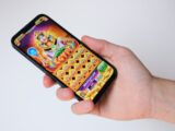 A hand holds a phone with an egyptian-themed game