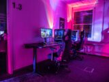 a room with a desk, computer, and two monitors