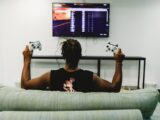 man sitting on couch holding controllers