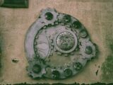 Ornate metal gearwork decoration on a textured wall