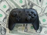 a video game controller sitting on top of a pile of money