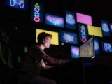 A focused gamer plays e-sports in a neon-lit room, surrounded by digital screens.