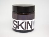 a jar of skin paste sitting on a white surface
