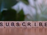 A wooden block spelling subscribe on a table