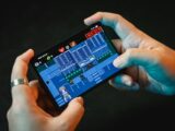 Hands playing a pixelated video game on a smartphone